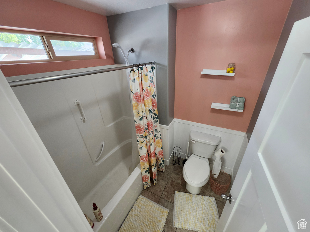 Bathroom featuring wainscoting, toilet, shower / tub combo, and tile patterned floors