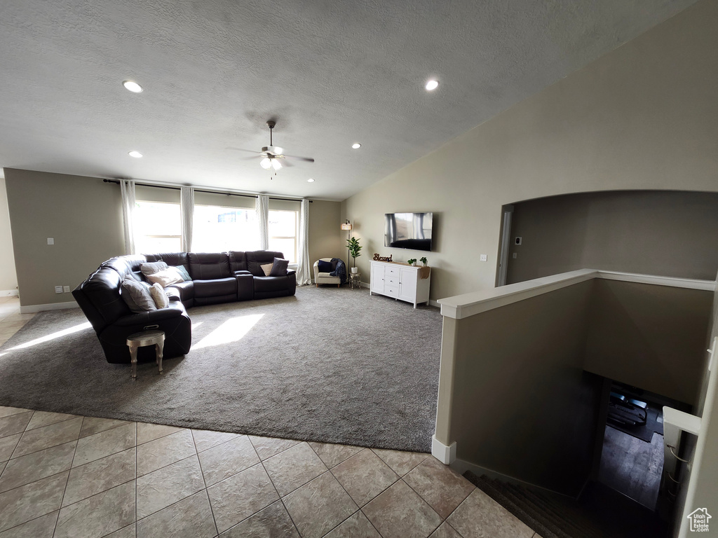 Carpeted living room featuring a ceiling fan, baseboards, recessed lighting, tile patterned floors, and vaulted ceiling