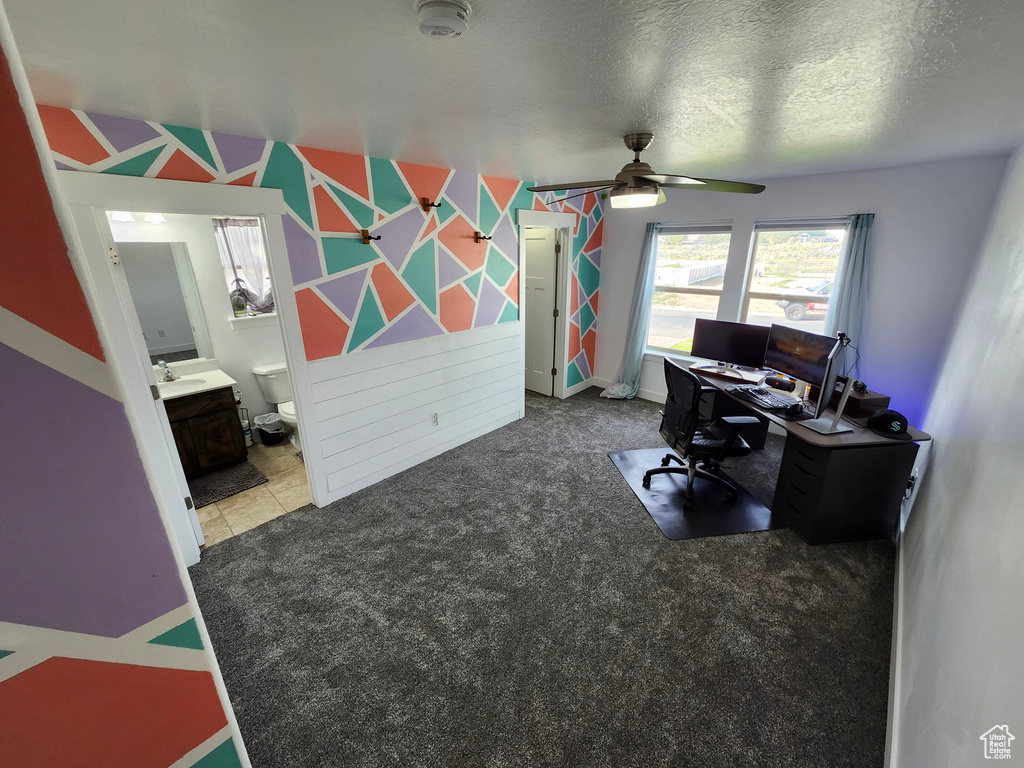 Office area featuring a ceiling fan, a sink, and a textured ceiling