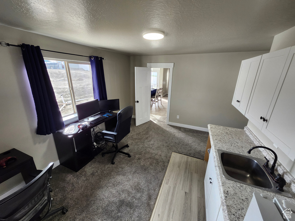 Office space with a sink, a textured ceiling, dark carpet, and baseboards