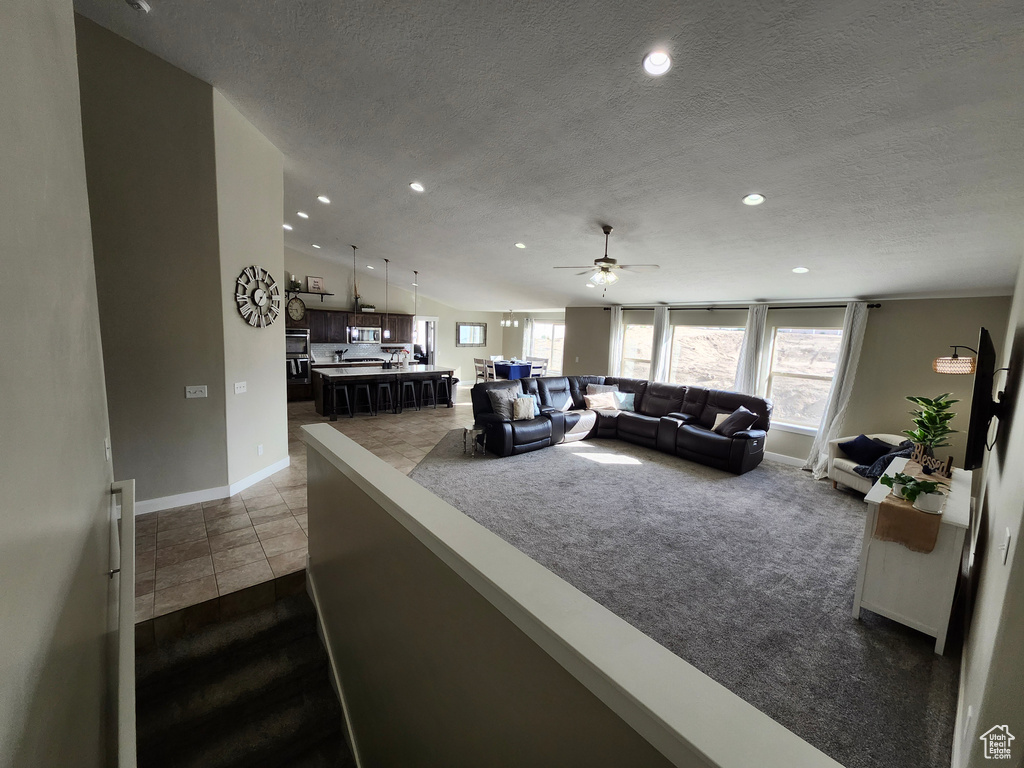 Living area with baseboards, a textured ceiling, a ceiling fan, recessed lighting, and dark colored carpet