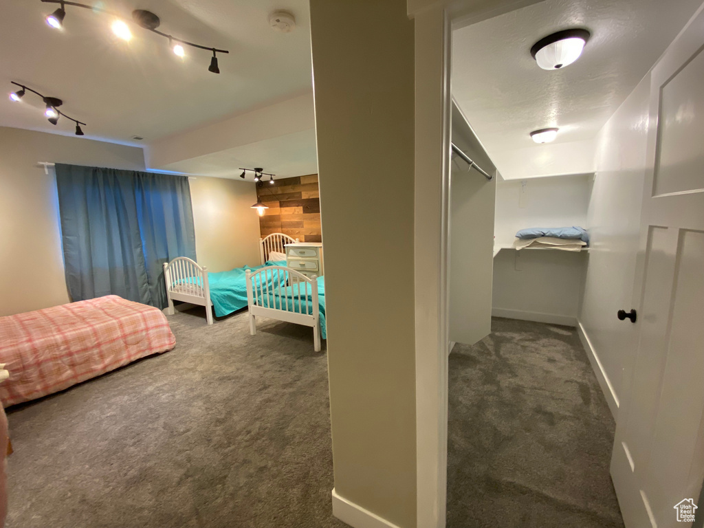 Bedroom with carpet floors, rail lighting, and baseboards