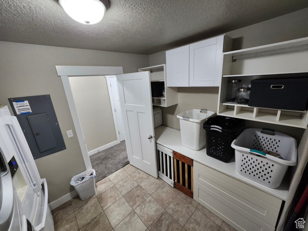 Mudroom with electric panel, a textured ceiling, and baseboards