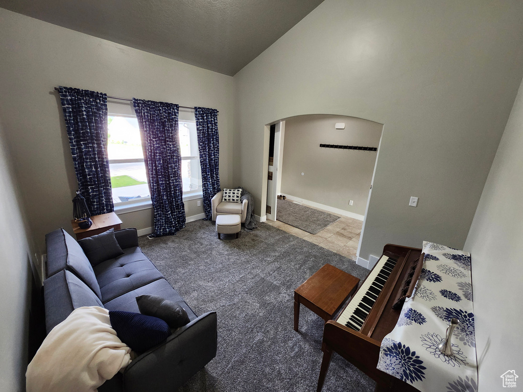 Carpeted living room featuring arched walkways, lofted ceiling, and baseboards