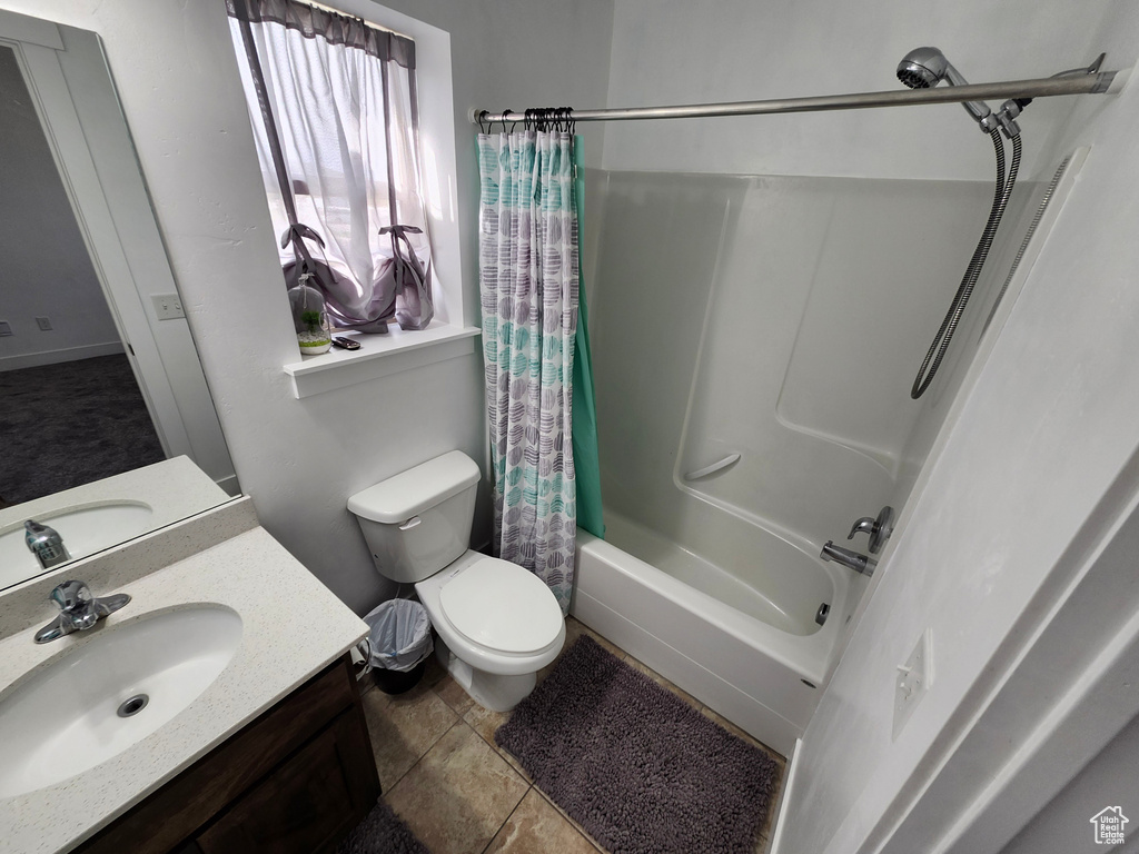 Bathroom featuring shower / bath combo with shower curtain, toilet, vanity, and tile patterned floors