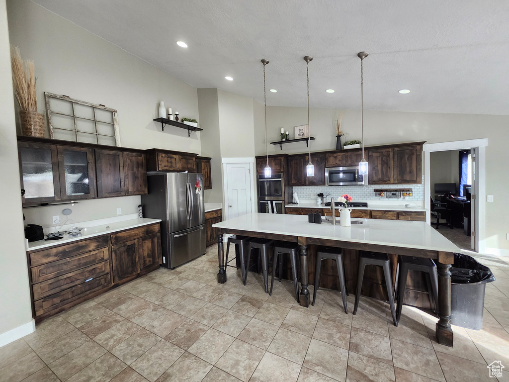 Kitchen with stainless steel appliances, a breakfast bar area, light countertops, backsplash, and recessed lighting