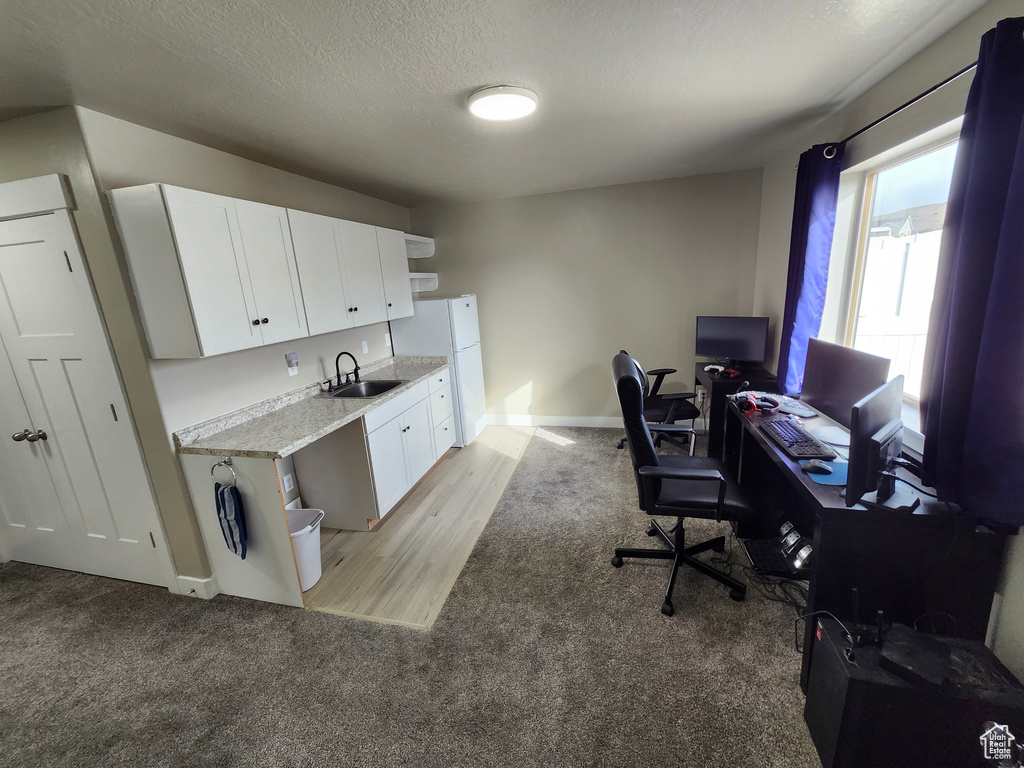 Home office featuring a sink, light colored carpet, baseboards, and a textured ceiling