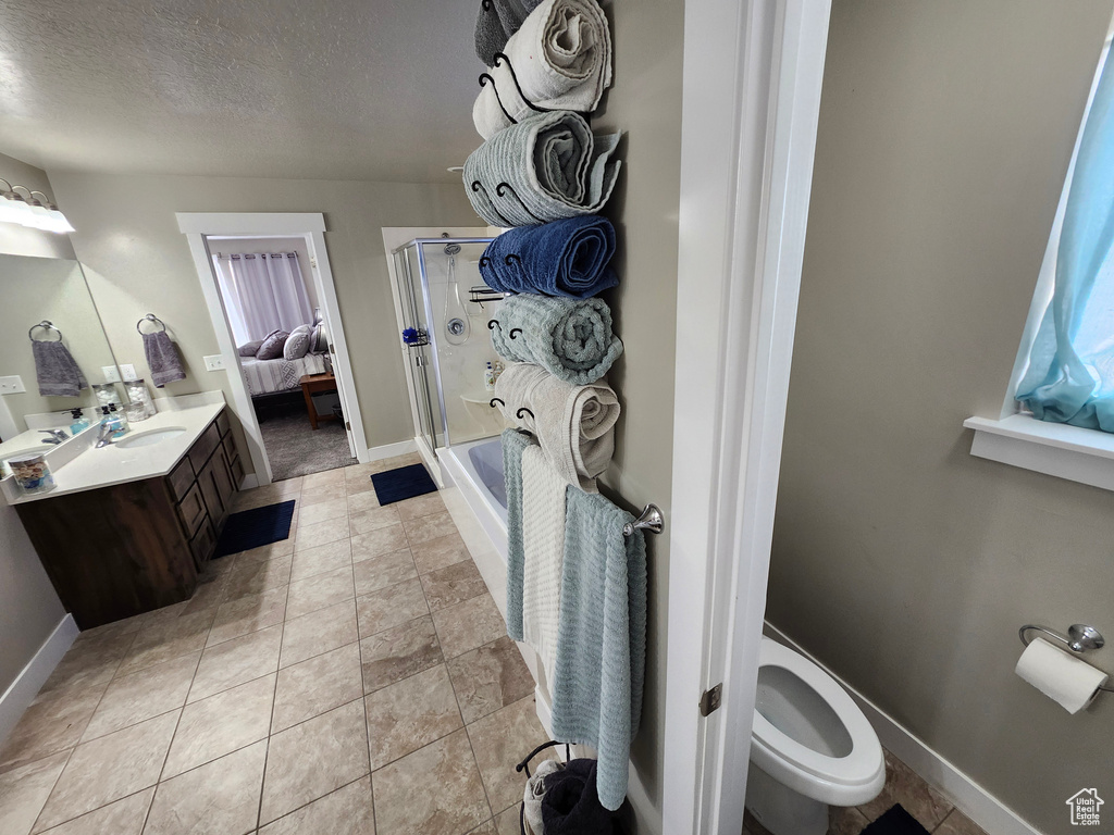 Full bathroom with a stall shower, baseboards, a textured ceiling, toilet, and vanity