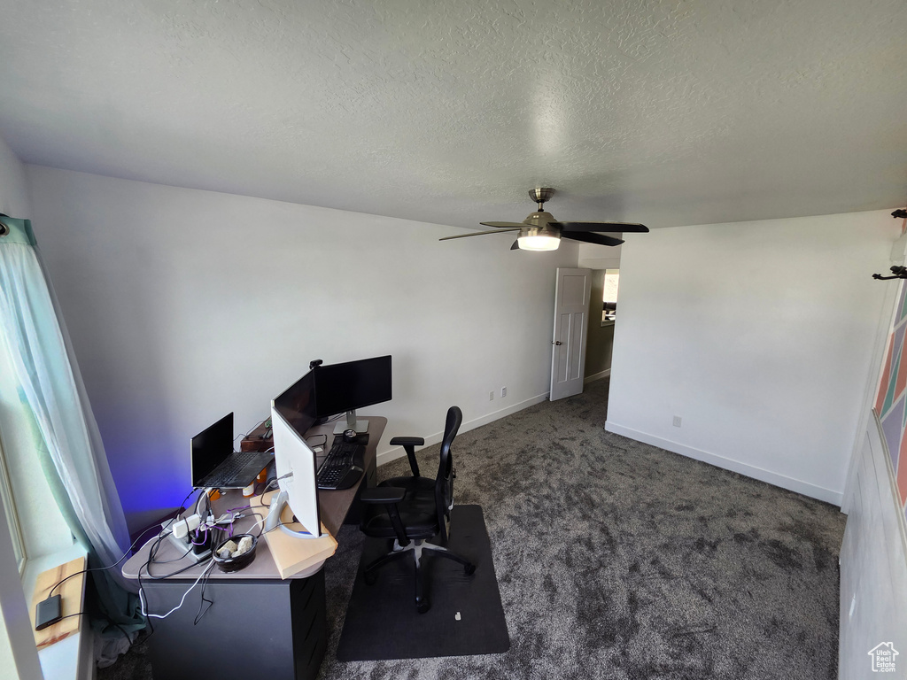 Carpeted office space with a textured ceiling, a ceiling fan, and baseboards