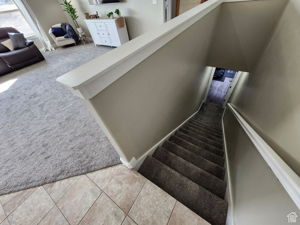 Staircase featuring carpet and tile patterned floors
