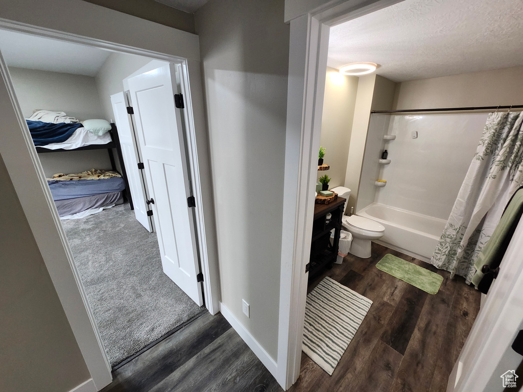 Full bathroom featuring wood finished floors, shower / bath combination with curtain, vanity, and toilet
