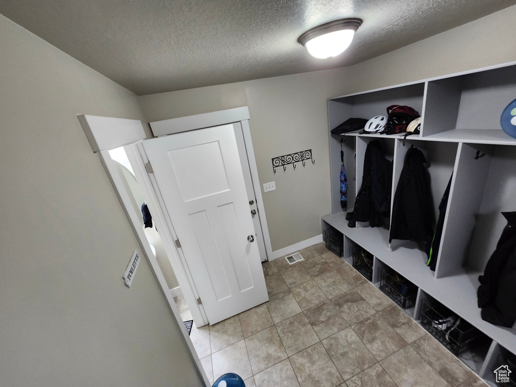 Mudroom with a textured ceiling and baseboards