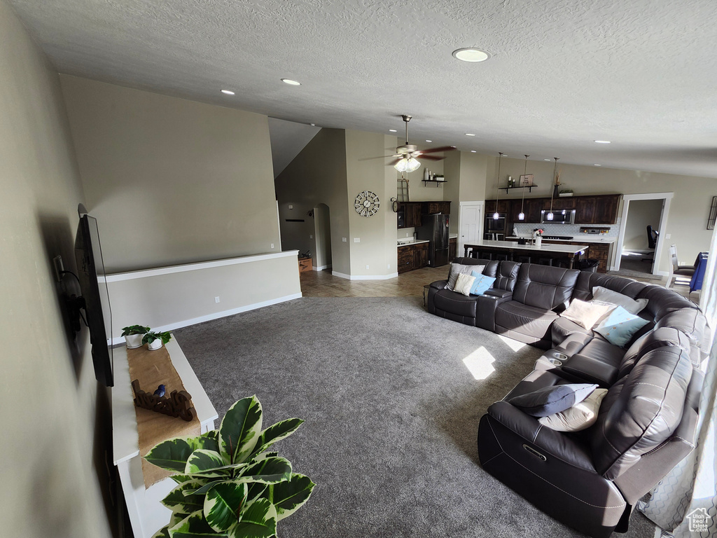 Living area with lofted ceiling, a ceiling fan, recessed lighting, a textured ceiling, and baseboards