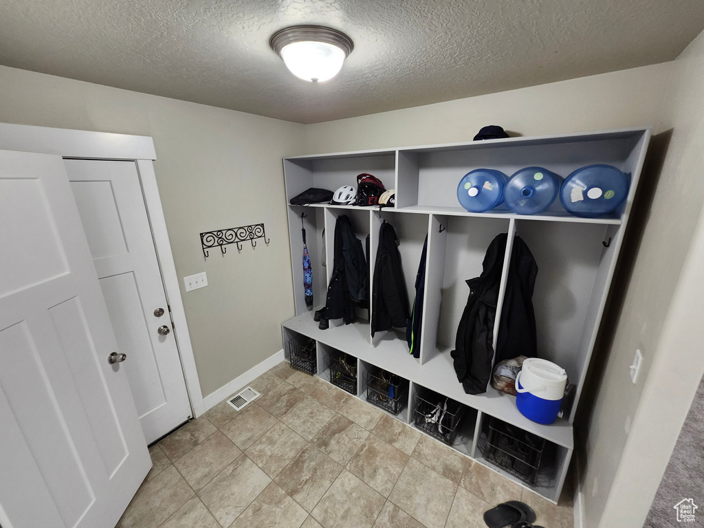 Mudroom featuring a textured ceiling and baseboards