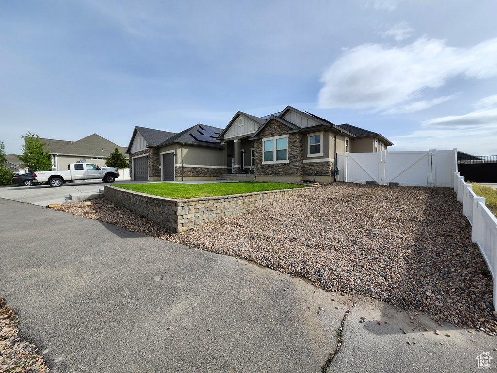 View of front of property with a gate, stone siding, board and batten siding, fence, and driveway