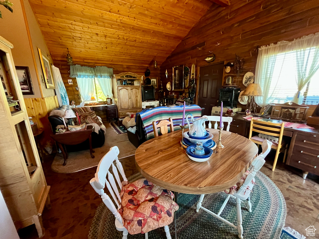 Dining room with wood walls, plenty of natural light, vaulted ceiling, and wooden ceiling