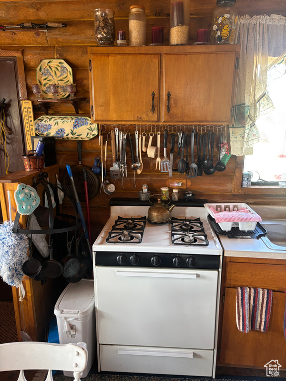 Kitchen featuring white gas stove, brown cabinets, and light countertops