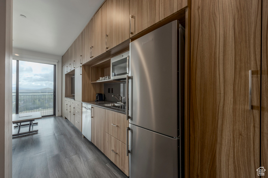 Kitchen with appliances with stainless steel finishes, a sink, modern cabinets, open shelves, and dark wood finished floors
