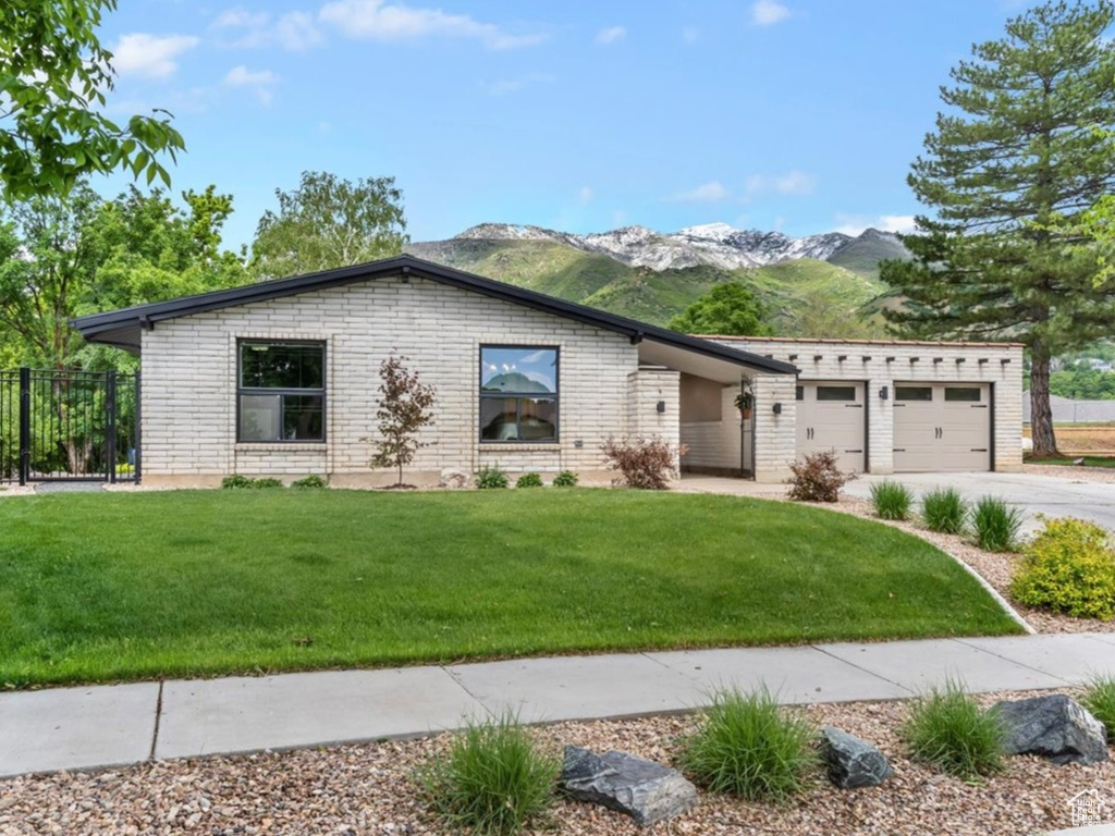 View of front of home with driveway, a mountain view, an attached garage, and brick siding