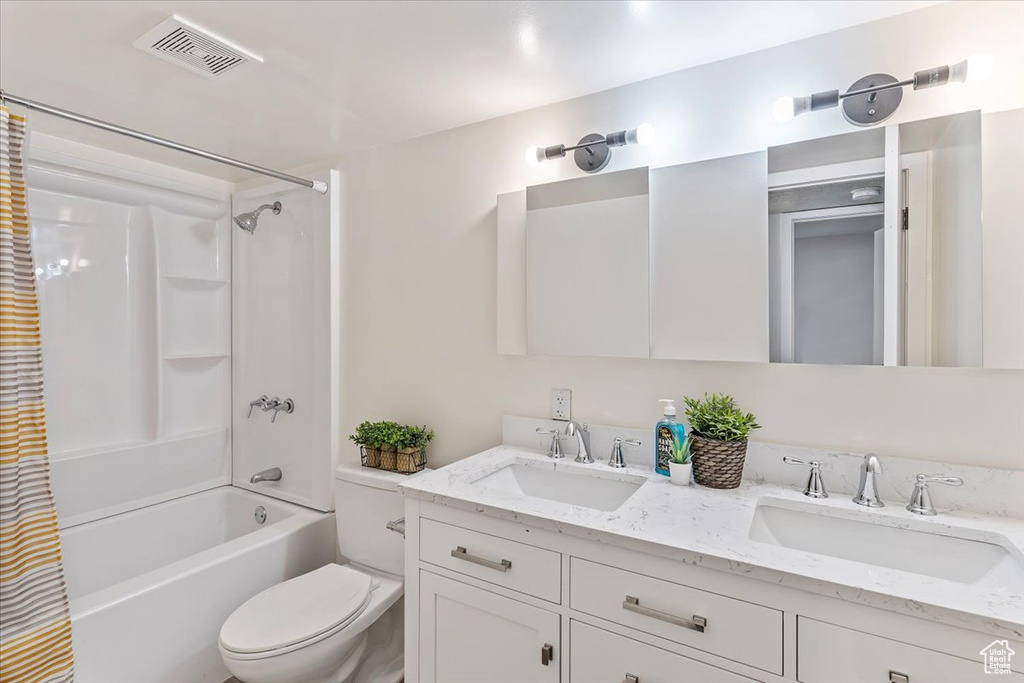 Bathroom featuring shower / tub combo, toilet, and double vanity