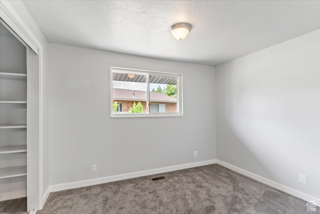 Spare room featuring carpet floors, baseboards, and a textured ceiling
