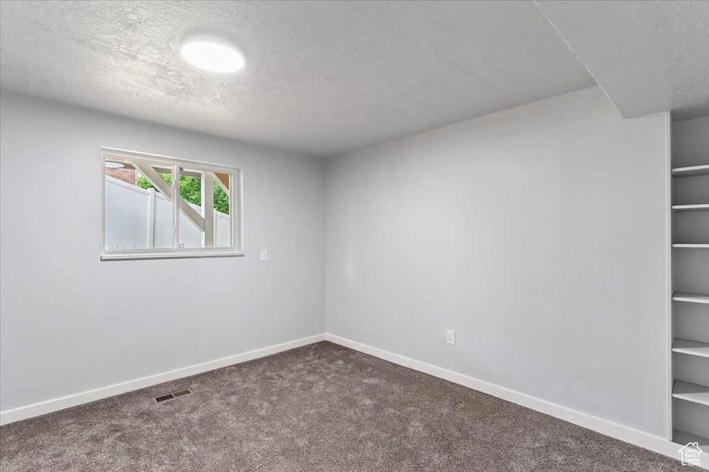 Spare room featuring a textured ceiling, carpet floors, and baseboards
