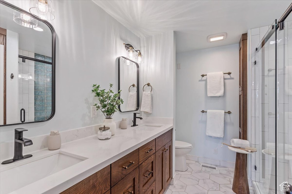 Full bathroom featuring toilet, a stall shower, tile patterned flooring, and double vanity