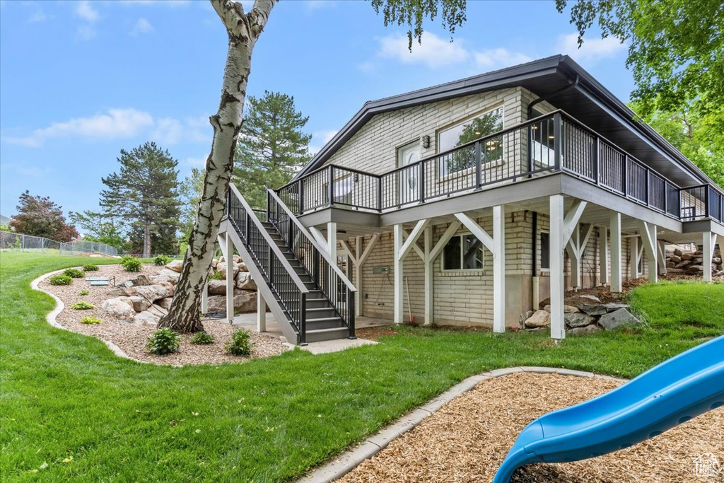 Rear view of property featuring a deck, a playground, and stairway