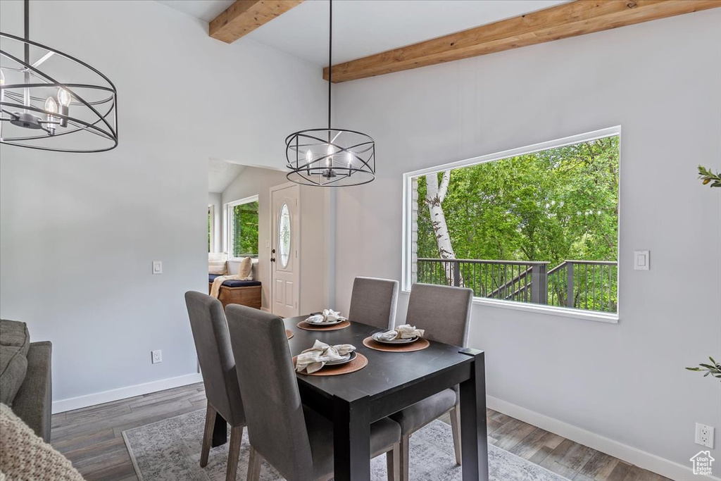 Dining room with a chandelier, beamed ceiling, baseboards, and dark wood-style flooring