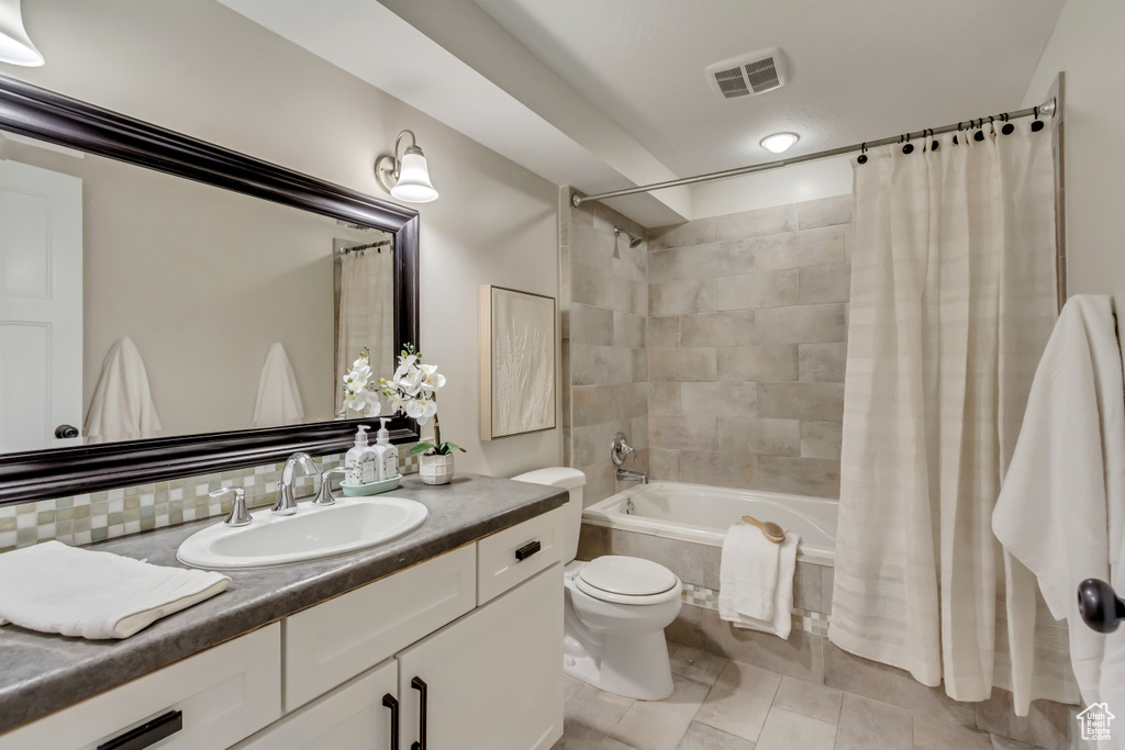 Bathroom with tiled shower / bath combo, toilet, vanity, and tile patterned flooring