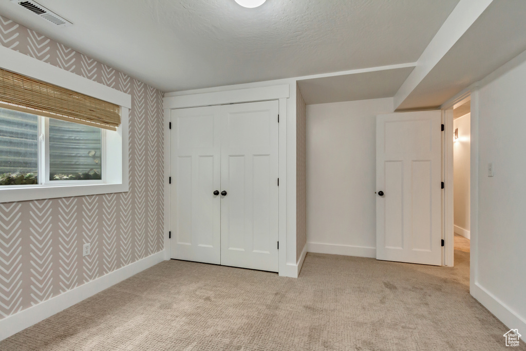 Unfurnished bedroom with carpet floors, baseboards, wallpapered walls, and a closet