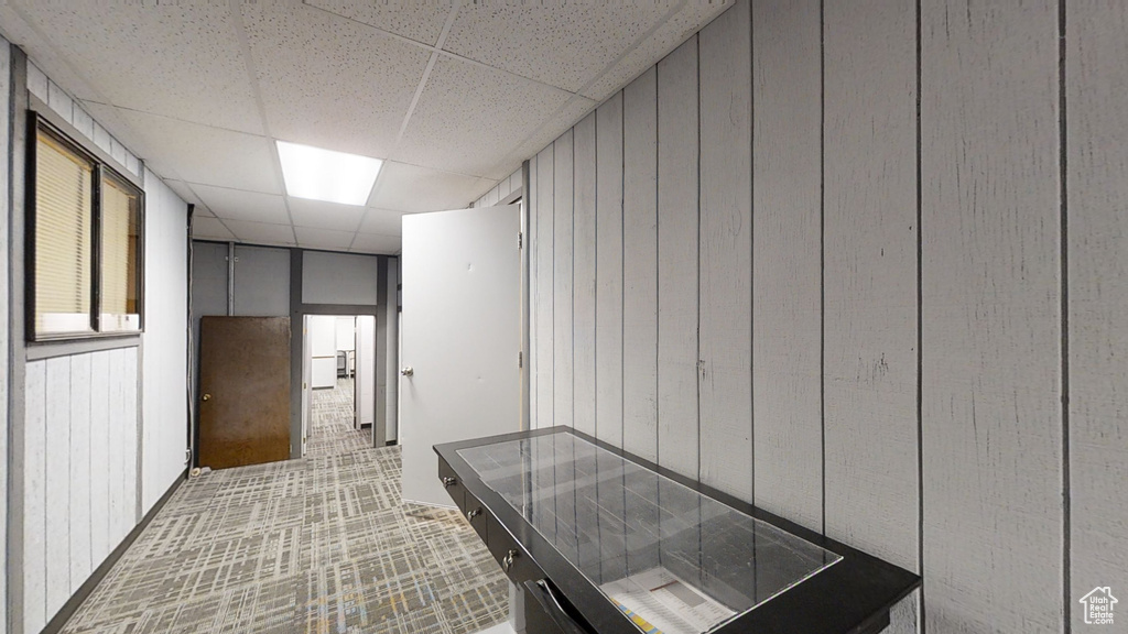 Corridor featuring a paneled ceiling and wood walls