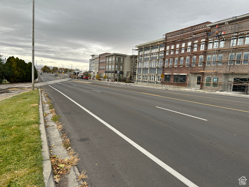 View of asphalt road featuring sidewalks and curbs