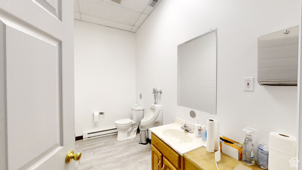 Bathroom featuring a baseboard heating unit, a drop ceiling, wood finished floors, toilet, and vanity