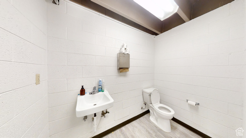 Bathroom featuring toilet, a sink, and wood finished floors