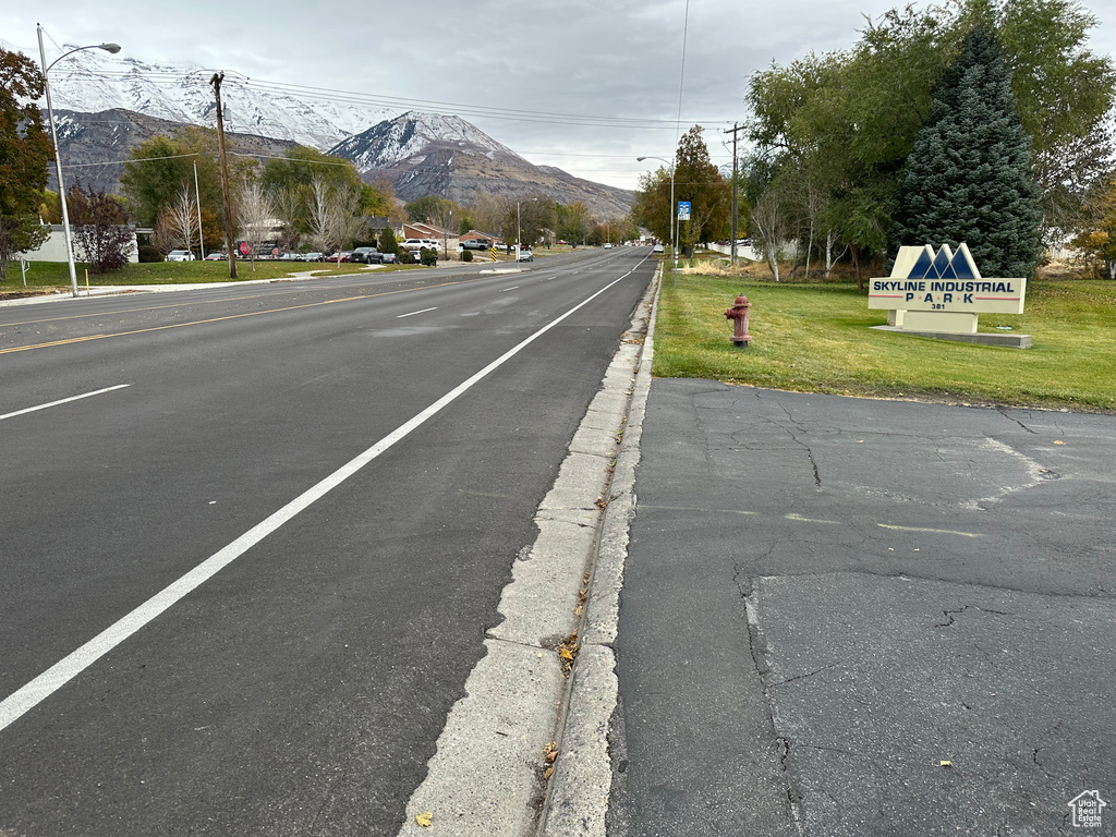 View of asphalt road featuring a mountain view, street lights, and curbs