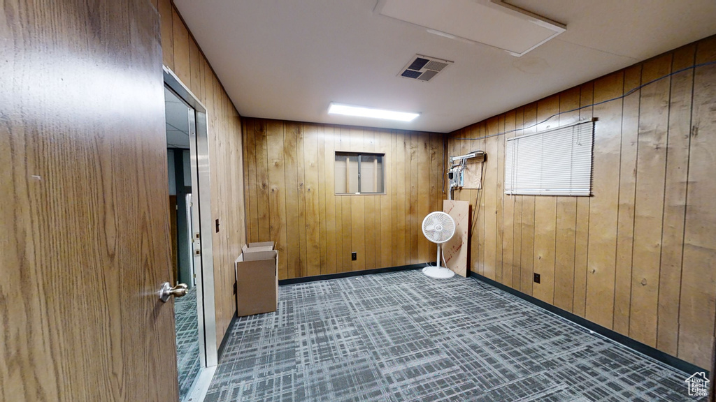 Empty room with wood walls, baseboards, and attic access