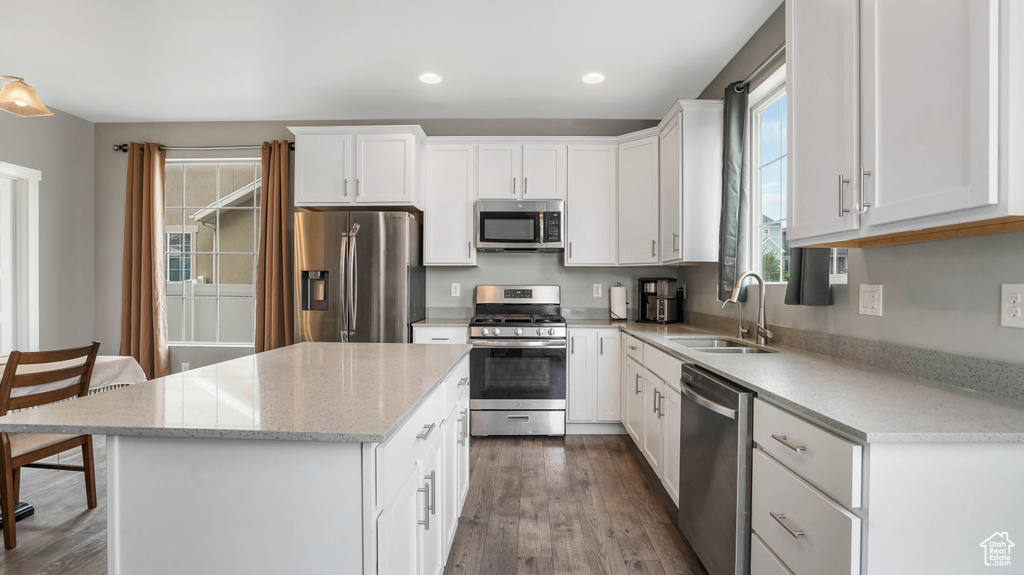 Kitchen featuring stainless steel appliances, a sink, dark wood-style flooring, a kitchen island, and white cabinets