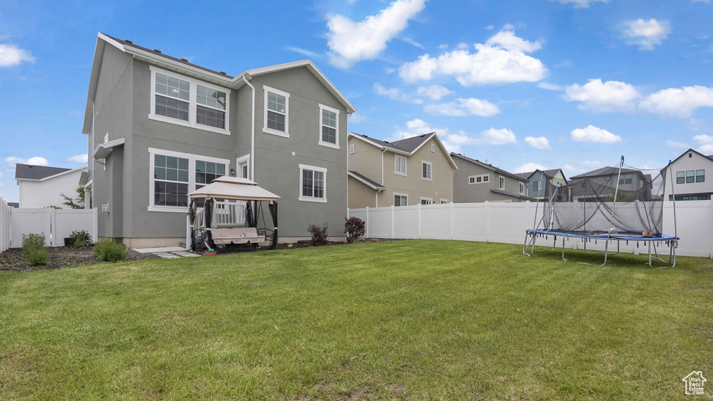 Rear view of house featuring a gazebo, a residential view, a trampoline, and stucco siding