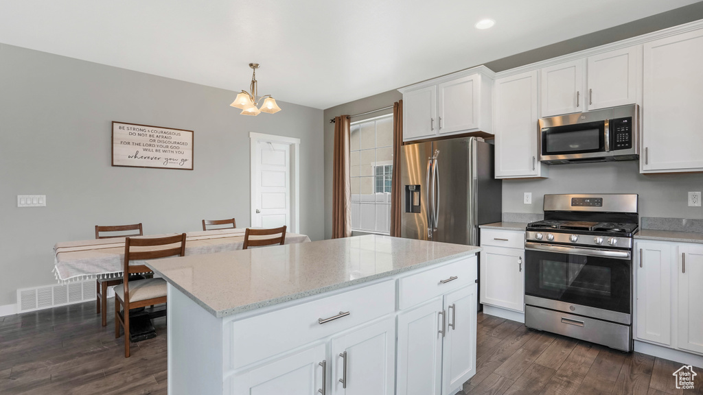 Kitchen with stainless steel appliances, dark wood-style floors, white cabinetry, and light stone countertops