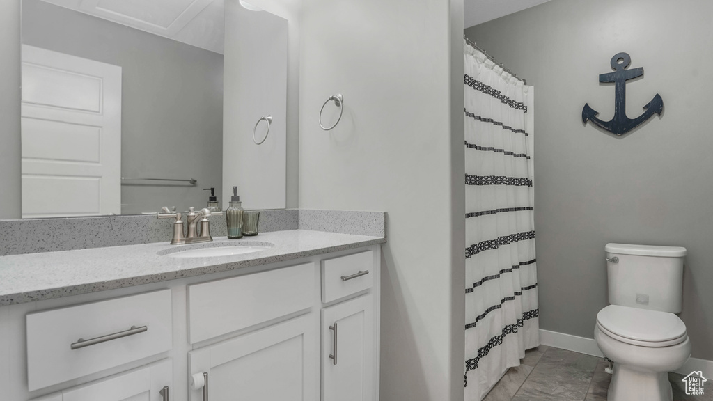 Full bathroom with toilet, baseboards, vanity, and curtained shower