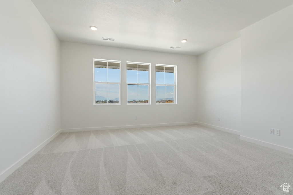Unfurnished room with light colored carpet and baseboards