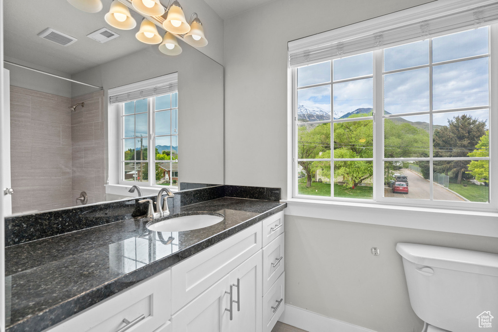 Bathroom featuring a chandelier, baseboards, toilet, vanity, and a shower