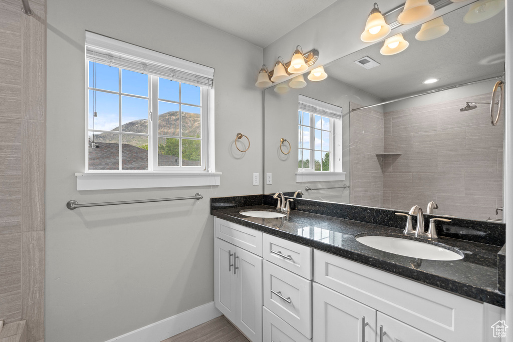 Bathroom featuring tiled shower, double vanity, baseboards, and a mountain view
