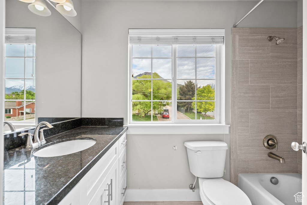Full bathroom featuring baseboards, toilet, vanity, and shower / washtub combination