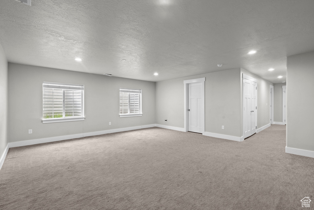 Spare room featuring recessed lighting, carpet floors, a textured ceiling, and baseboards
