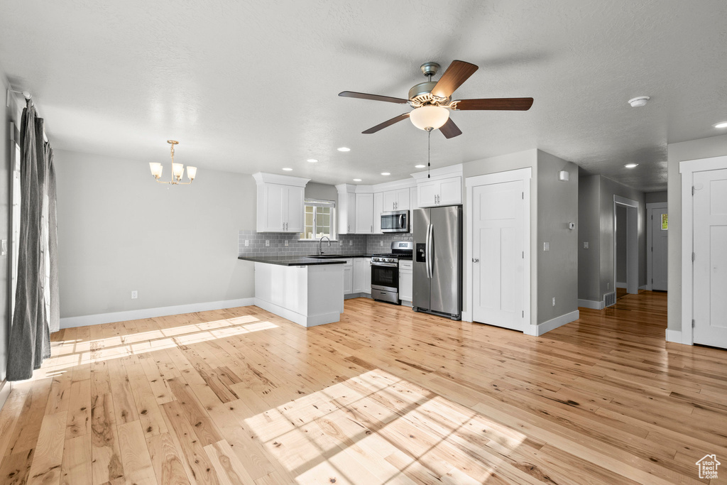 Kitchen featuring appliances with stainless steel finishes, a chandelier, recessed lighting, tasteful backsplash, and light wood-style floors