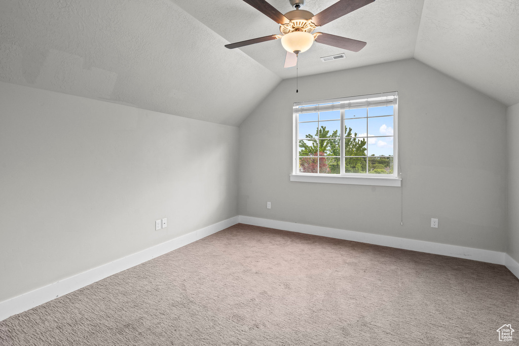 Bonus room featuring vaulted ceiling, a ceiling fan, a textured ceiling, carpet floors, and baseboards