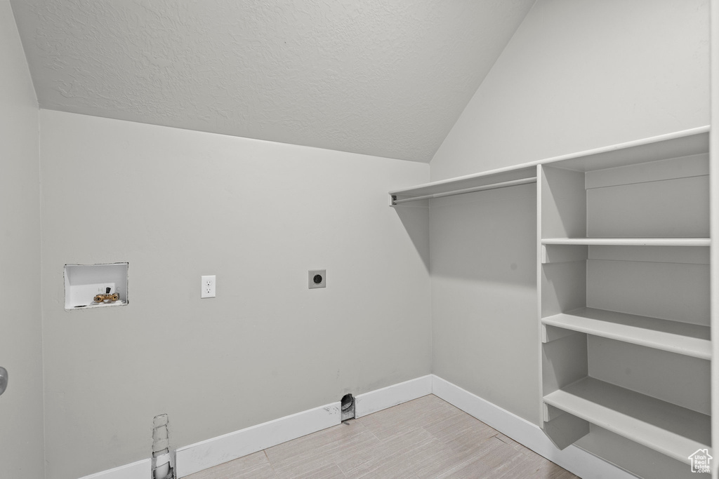 Washroom with electric dryer hookup, washer hookup, baseboards, wood finished floors, and a textured ceiling