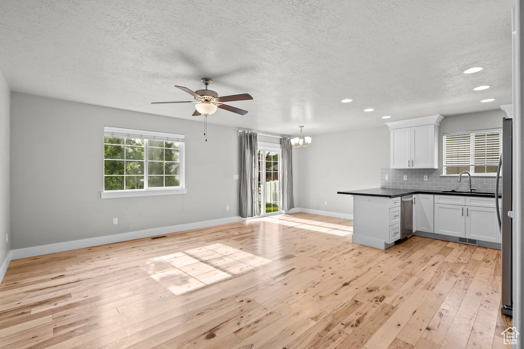 Kitchen featuring stainless steel appliances, open floor plan, a sink, ceiling fan, and white cabinets